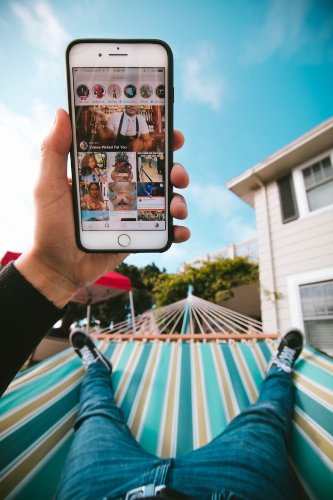 Man relaxing on hammock scrolls feed to strategize for an Instagram marketing agency.
